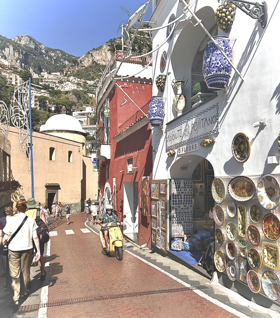 Amalfi Coast street with ceramic shop, textured tiles, and a yellow Vespa, highlighting color and detail in coastal design