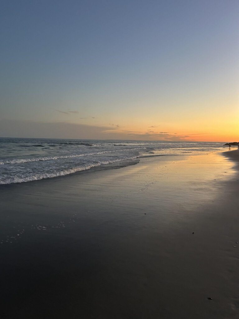 Warm sunset over the ocean with soft peach and blue tones inspiring romantic coastal wedding invitation color palettes