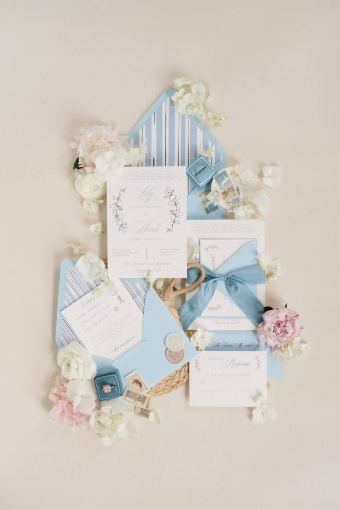 Coastal blue wedding invitation suite with ribbon, envelope liner, and floral styling