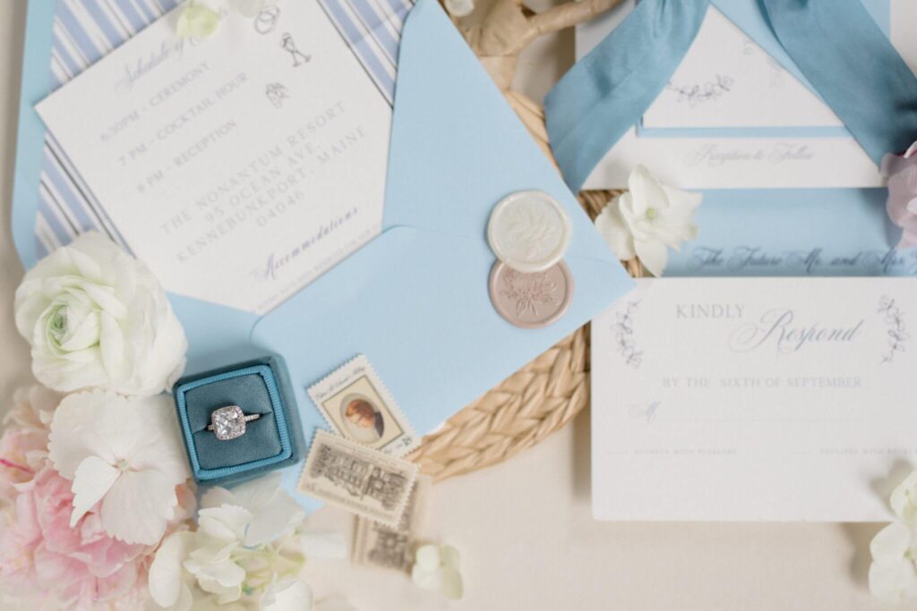 Elegant coastal blue wedding invitation details including envelope, wax seal, ribbon, and vintage stamps