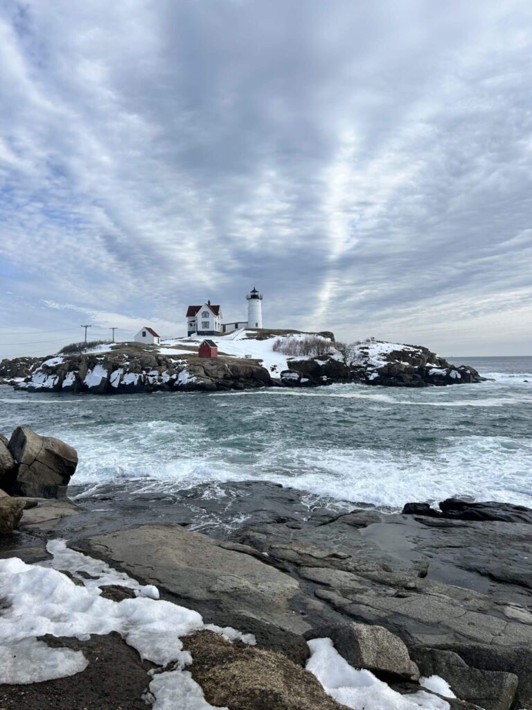 Rocky coastal shoreline with lighthouse and muted ocean blues and grays inspiring an elegant coastal wedding invitation color palette