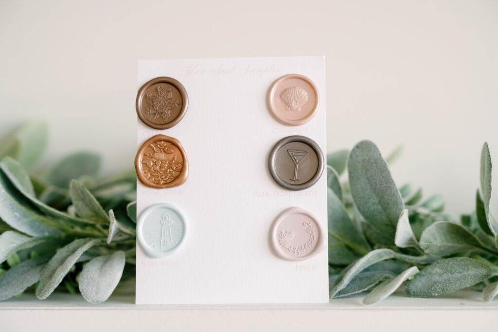 Custom wax seal color options for luxury wedding invitations in soft coastal tones with floral and shell designs