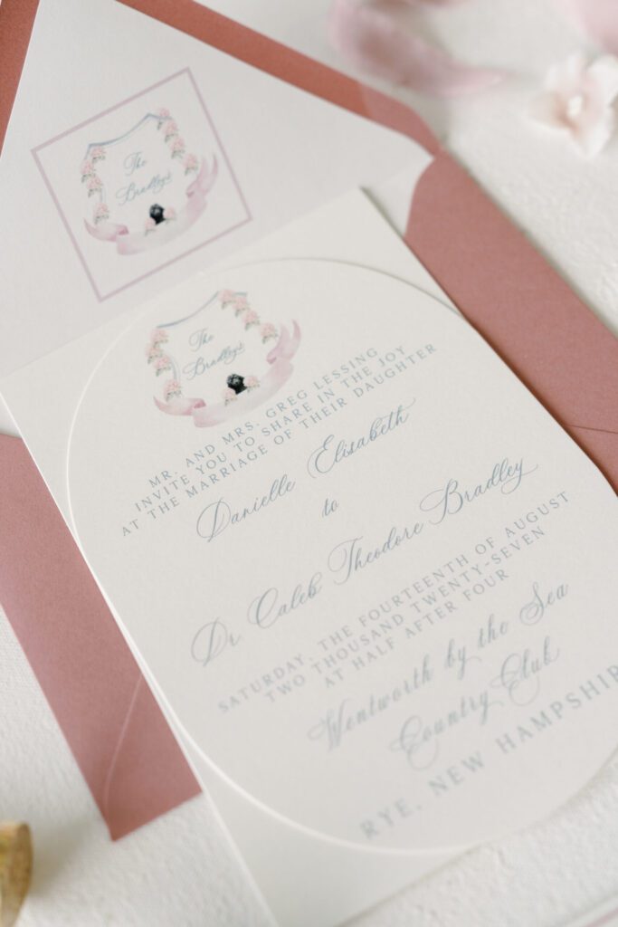 Custom wedding crest featuring a dog illustration inside a soft blush envelope