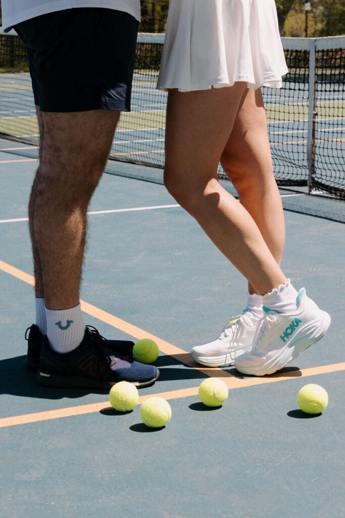 Closeup of pickleball court details featuring tennis balls, athletic shoes, and an editorial engagement session aesthetic.
